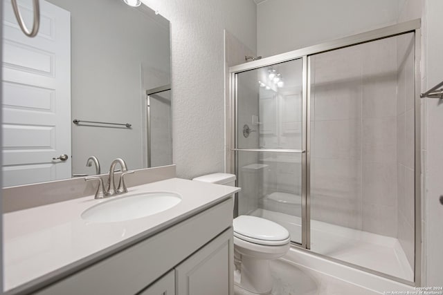 full bathroom with vanity, a shower stall, toilet, and a textured wall