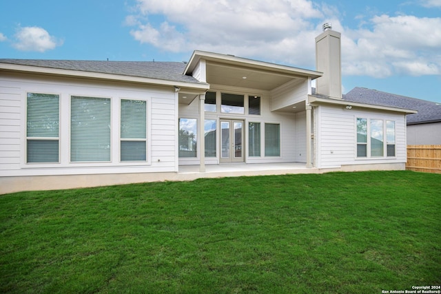 back of house featuring a patio, a lawn, a chimney, and fence