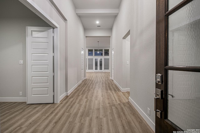 hall with visible vents, wood finished floors, and baseboards