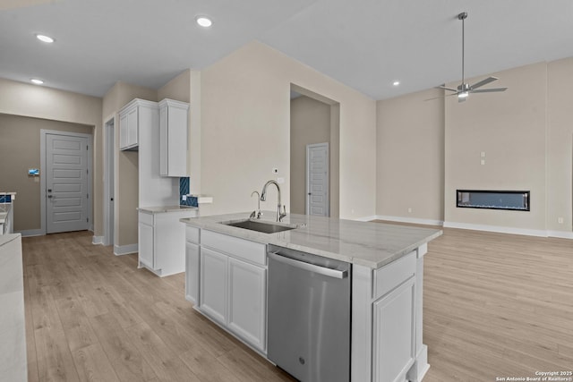 kitchen featuring a glass covered fireplace, light wood finished floors, white cabinetry, a sink, and stainless steel dishwasher