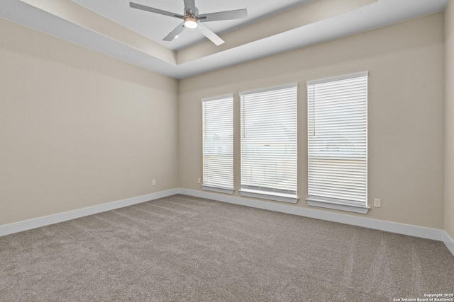 unfurnished room featuring baseboards, a tray ceiling, carpet, and a ceiling fan