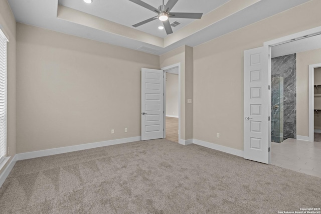 unfurnished bedroom with a tray ceiling, baseboards, carpet, and visible vents