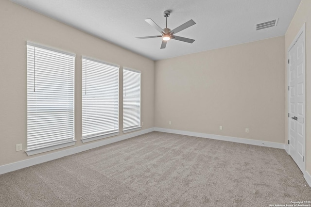 carpeted empty room with visible vents, baseboards, and ceiling fan