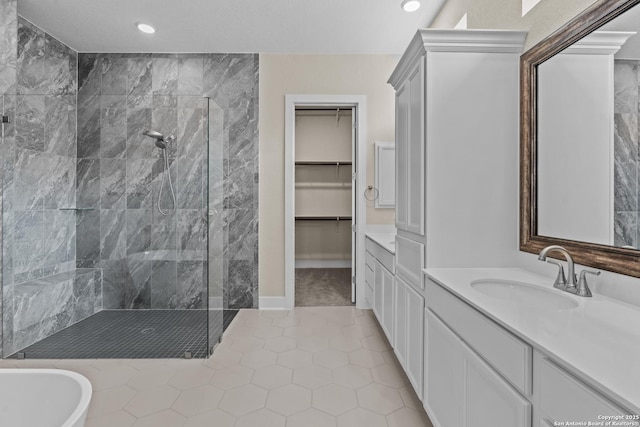 full bath with vanity, recessed lighting, a tile shower, tile patterned flooring, and a walk in closet