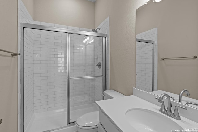 full bath featuring vanity, a shower stall, toilet, and a textured wall