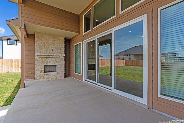 view of patio featuring an outdoor stone fireplace and fence