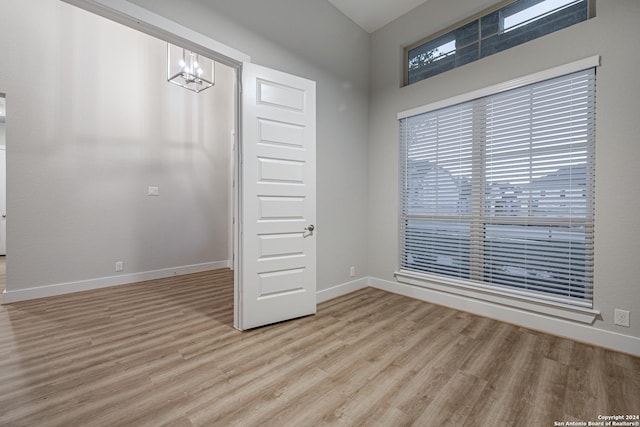 empty room with a notable chandelier and light hardwood / wood-style flooring