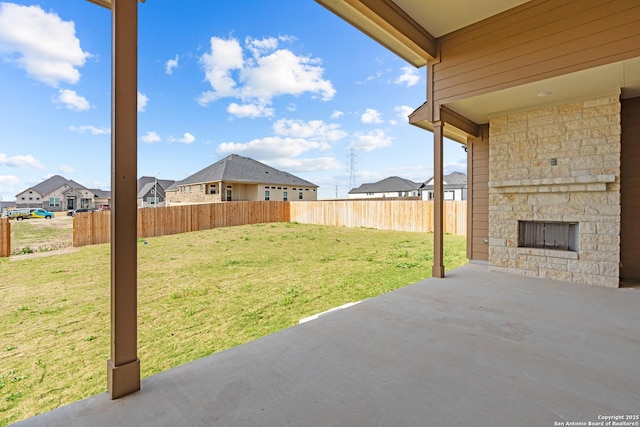 view of yard with a patio, fence, a residential view, and an outdoor stone fireplace