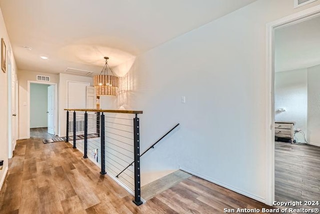 hallway featuring an inviting chandelier and hardwood / wood-style floors