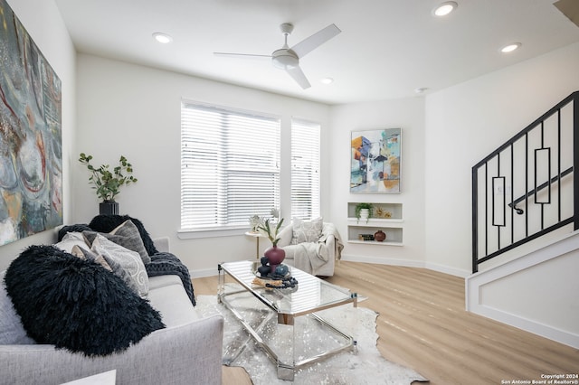 living room featuring ceiling fan, built in features, and light hardwood / wood-style flooring