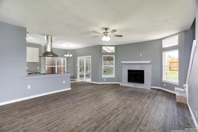 unfurnished living room with dark wood-type flooring and ceiling fan with notable chandelier