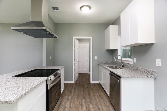 kitchen featuring appliances with stainless steel finishes, wall chimney range hood, sink, white cabinetry, and wood-type flooring