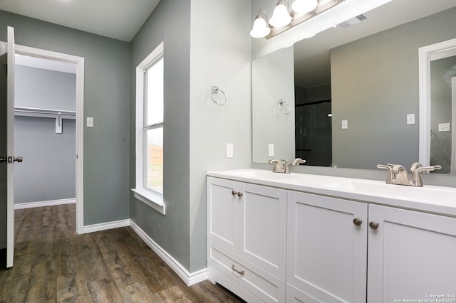 bathroom with double vanity, a shower, and hardwood / wood-style floors