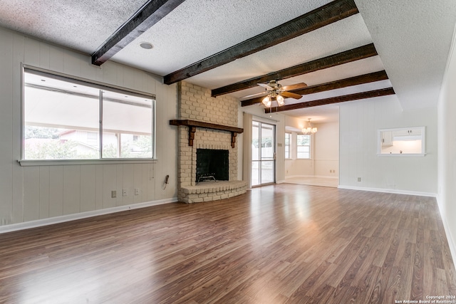 unfurnished living room with wood-type flooring, a textured ceiling, a brick fireplace, and a healthy amount of sunlight