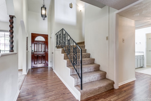 entryway featuring hardwood / wood-style flooring, a towering ceiling, and a textured ceiling