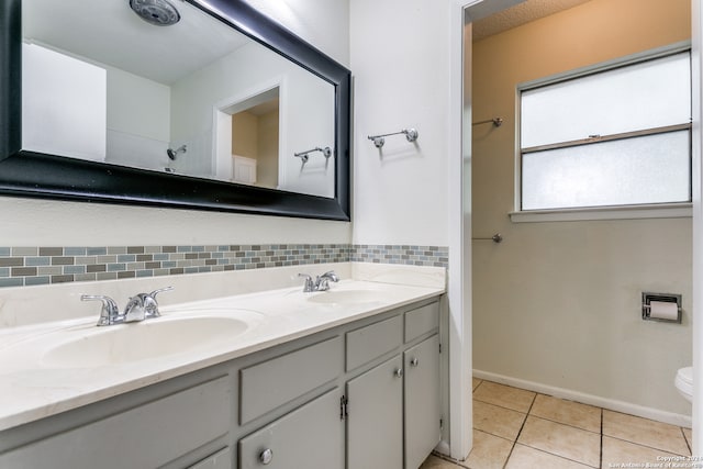 bathroom featuring toilet, tasteful backsplash, tile patterned flooring, and double vanity