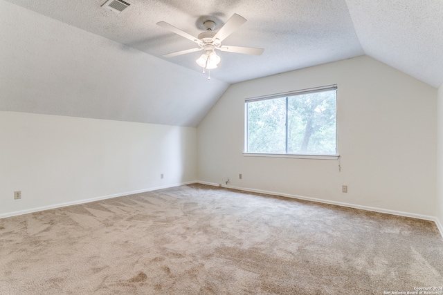 bonus room featuring light carpet, vaulted ceiling, a textured ceiling, and ceiling fan