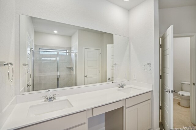 bathroom with toilet, vanity, and a shower with shower door