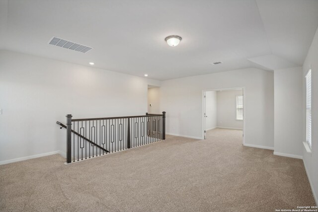 unfurnished room with vaulted ceiling and light colored carpet