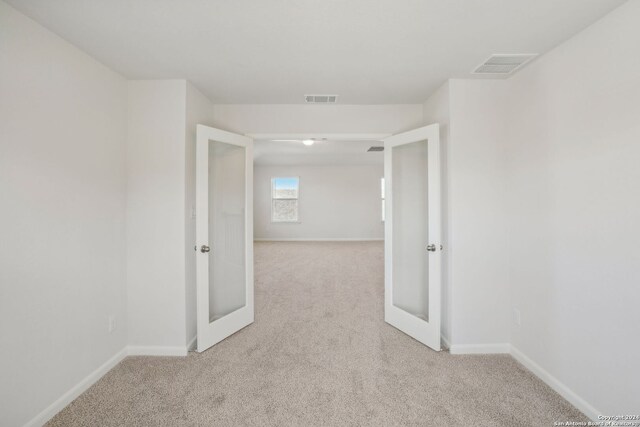 hallway with light carpet and french doors