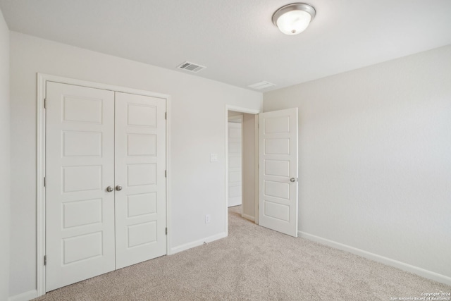 unfurnished bedroom with light carpet and a closet