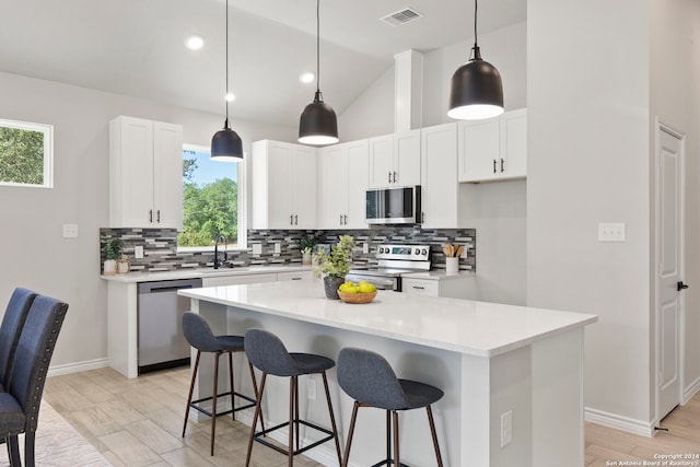 kitchen featuring stainless steel appliances, plenty of natural light, white cabinetry, and a kitchen island