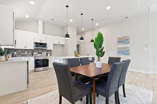 dining room with vaulted ceiling and light hardwood / wood-style floors