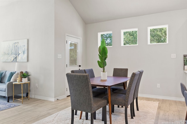 dining area with light wood-type flooring and lofted ceiling