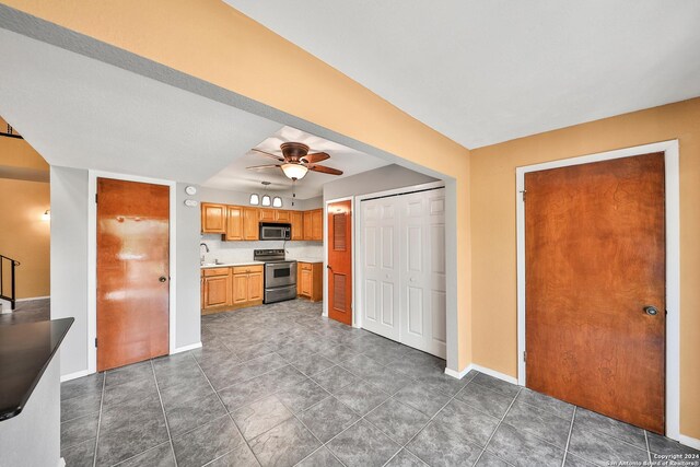 kitchen with dark tile patterned floors, appliances with stainless steel finishes, sink, and ceiling fan