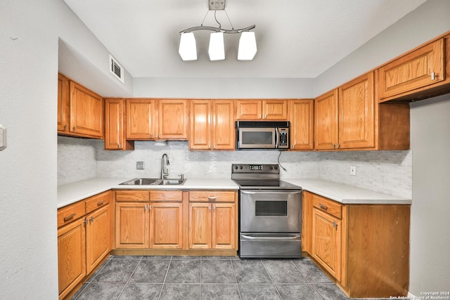 kitchen with pendant lighting, sink, decorative backsplash, and appliances with stainless steel finishes