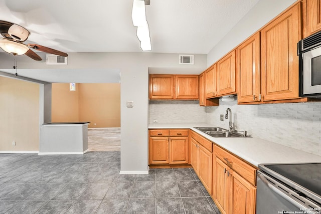 kitchen featuring ceiling fan, dark tile patterned floors, sink, and backsplash