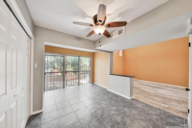 tiled spare room with ceiling fan