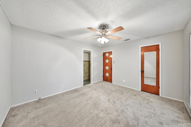 empty room with ceiling fan, light carpet, and a textured ceiling