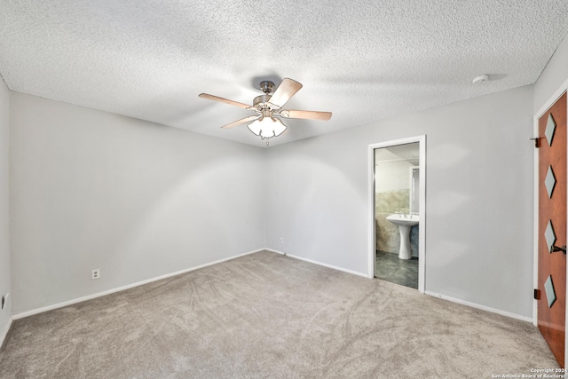 unfurnished bedroom with ensuite bathroom, sink, a textured ceiling, carpet floors, and ceiling fan