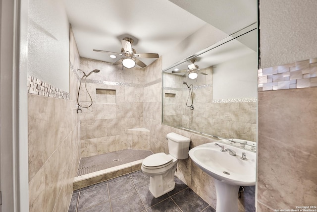 bathroom featuring toilet, sink, tile walls, a tile shower, and tile patterned flooring