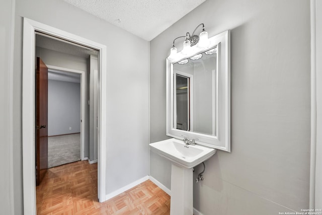 bathroom featuring parquet floors, sink, and a textured ceiling