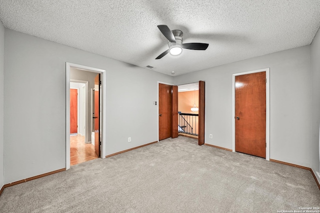 unfurnished bedroom featuring ceiling fan, connected bathroom, light carpet, and a textured ceiling