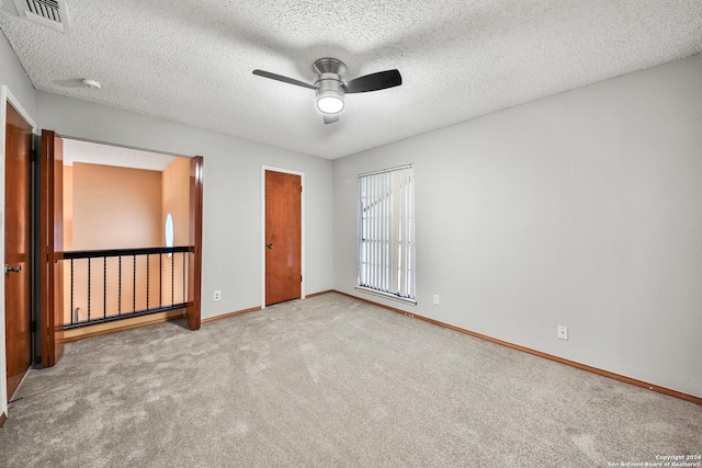 unfurnished bedroom with ceiling fan, light colored carpet, and a textured ceiling