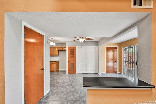 kitchen featuring tile patterned flooring, ceiling fan, and a textured ceiling