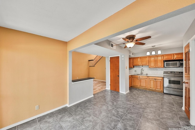 kitchen featuring sink, ceiling fan, appliances with stainless steel finishes, backsplash, and dark tile patterned flooring