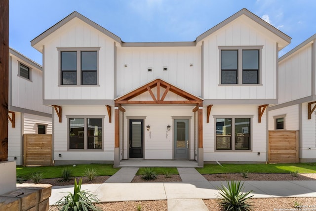 view of front of property with a front lawn, board and batten siding, and fence