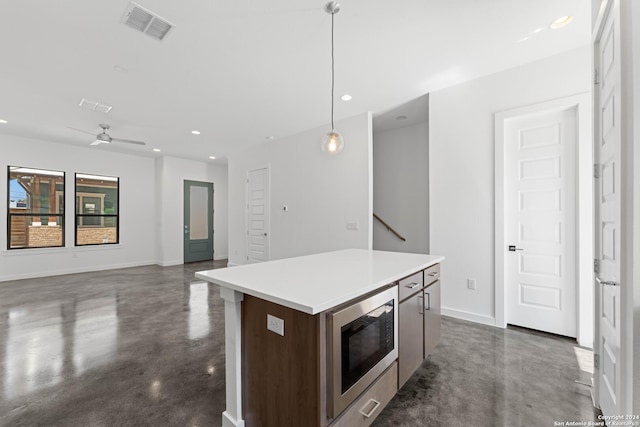 kitchen with built in microwave, ceiling fan, a center island, and pendant lighting