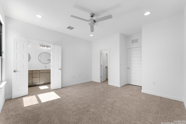 unfurnished bedroom featuring light carpet, connected bathroom, ceiling fan, and a closet