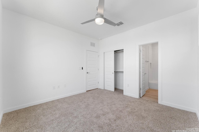 unfurnished bedroom featuring ceiling fan, ensuite bathroom, a closet, and light carpet