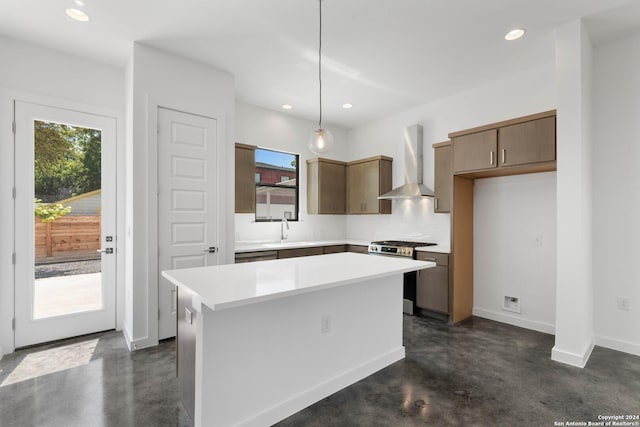 kitchen featuring sink, stainless steel gas range, hanging light fixtures, a center island, and wall chimney exhaust hood