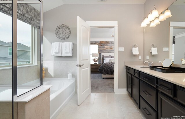 bathroom featuring tile patterned flooring, tiled bath, vaulted ceiling, and dual bowl vanity