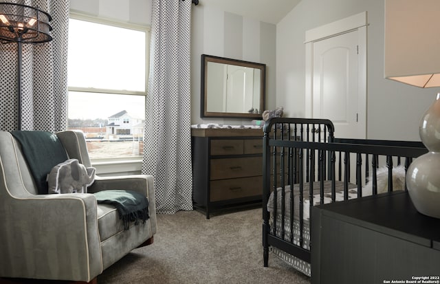 bedroom with a crib, light colored carpet, vaulted ceiling, and a chandelier