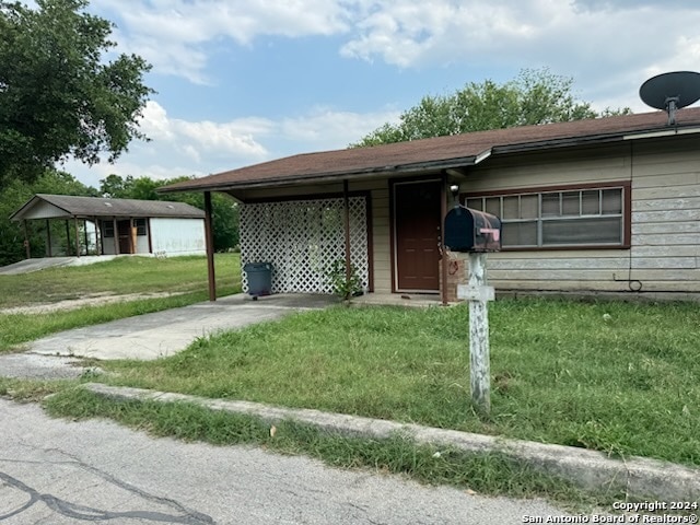 ranch-style house featuring a carport and a front lawn