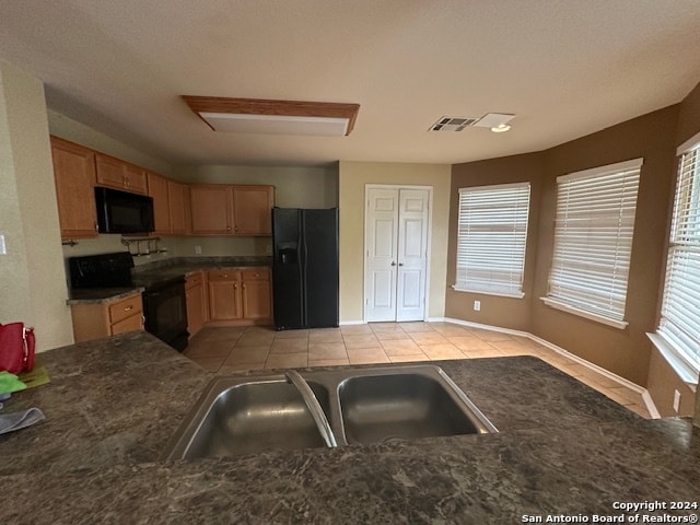 kitchen with light tile patterned floors, black appliances, and sink