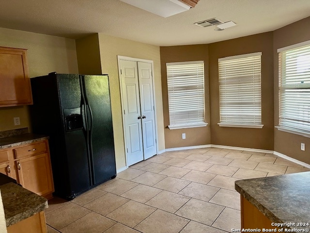 kitchen with black fridge and light tile patterned floors